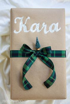 a present wrapped in brown paper with a green bow and name kaua on it