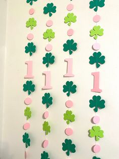 a green and pink number one hanging from a wall with shamrocks on it's sides