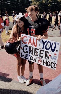 two young people standing next to each other holding signs