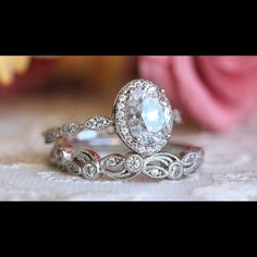 two wedding rings sitting on top of a table next to a rose budded flower