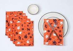 an orange halloween themed table setting with silverware and napkins