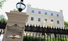 an iron fence surrounds the entrance to a large white building with a black gate and light post