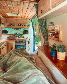 an interior view of a camper with plants on the counter and bed in the foreground