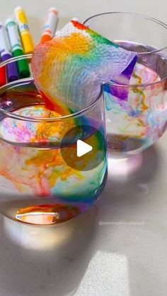 two glass bowls filled with different colored paints and crayons on top of each other