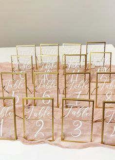 the table numbers are in gold frames with white calligraphy on pink tissue and linen