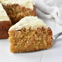 a piece of carrot cake with white frosting on a plate next to a fork