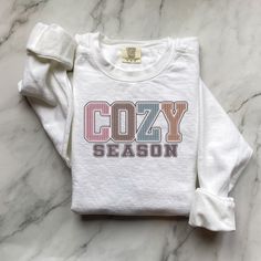 Fall Sweatshirt, Cozy Season Fall Sweatshirt, Cozy Season Merry Christmas, Christmas Sweatshirt, Winter Sweatshirt, Stay Home, Cozy Vibes Embrace the cozy vibes of fall and winter with our "Cozy Season" sweatshirt! Perfect for snuggling up at home, sipping hot cocoa, or celebrating the holidays in style. This soft and warm sweatshirt is your ultimate companion for chilly days and nights.  Available in festive "Merry Christmas" designs and classic fall styles. Luxurious comfort and style are what this unisex, garment-dyed sweatshirt is all about. It's made with 80% ring-spun cotton and 20% polyester and the fabric is 3-end garment-dyed, ring-spun, color-blast fleece with a 100% cotton face. Each sweatshirt comes with a relaxed fit, a rolled-forward shoulder, and a back neck patch.  .: 80% r Cozy Cotton T-shirt For Loungewear, Cozy Fit Letter Print Sweater For Loungewear, Cozy Crew Neck T-shirt For Loungewear, Cozy Fit Sweater With Letter Print For Loungewear, Cozy Fit Soft-washed Sweater, Cozy Letter Print Sweater For Loungewear, White Cotton Comfy Sweater, Comfy White Cotton Sweater, Cozy Cotton Sweater With Letter Print