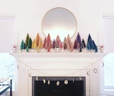 a fireplace with christmas trees on it and a mirror above the fire place in the room