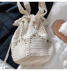 a crocheted bag sitting on top of a bed next to a wooden spoon