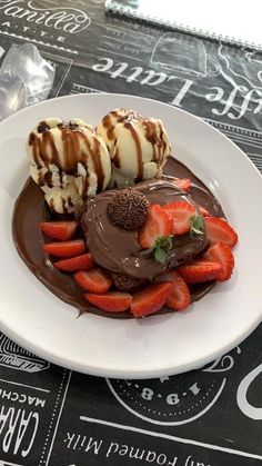 a white plate topped with chocolate covered strawberries and ice cream on top of a table