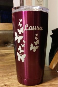 a purple tumbler with white butterflies on it