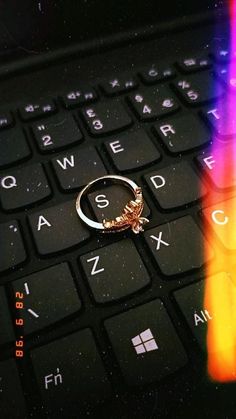 a ring sitting on top of a computer keyboard next to a rainbow colored key board