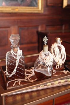 three bottles with pearls on them sitting on a table