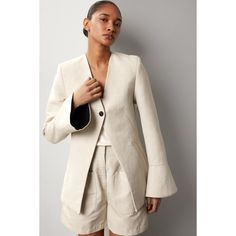 Beige virgin wool and hemp blend (50% Virgin Wool, 50% Hemp). Jacket. Long sleeves. Front button closure. 30" from shoulder to hemline. Imported. Fitted Linen Blazer With Button Cuffs, Elegant Linen Blazer With Button Cuffs, Chic Linen Outerwear With Buttons, Chic Linen Outerwear With Hidden Button Closure, Beige Blazer With Button Cuffs For Spring, Spring Beige Blazer With Button Cuffs, Tailored Linen Blazer With Button Cuffs, Spring Structured Blazer With Button Cuffs, Beige Linen Outerwear With Button Cuffs