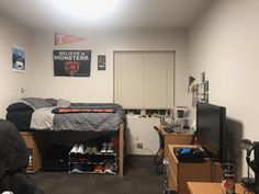 a dorm room with a bed, desk and television