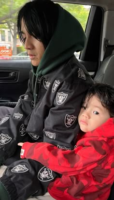 a young child sitting in the back seat of a car with an adult holding it