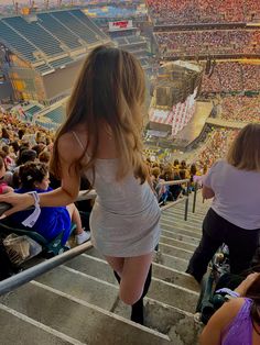 a woman is walking up the stairs at a concert in front of a large crowd