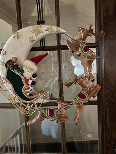 a santa clause sleigh with reindeers on it hanging from the side of a window