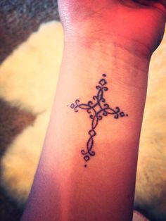 an image of a cross tattoo on someone's wrist and the other side of her arm