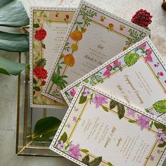 three cards with flowers on them sitting next to a plant and some other things in the background