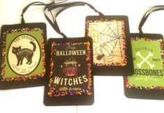 four halloween tags are hanging on a white wall and decorated with sprinkles