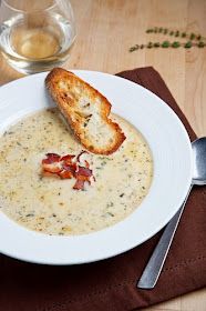 a white plate topped with soup next to a glass of wine