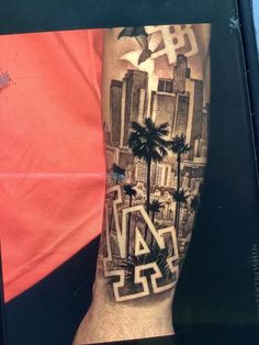 a man's arm with a cityscape and palm trees tattoo on it