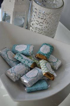 a white plate topped with lots of candy covered in gold wrappers next to a glass vase