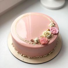 there is a pink cake with flowers on the top and gold trim around the edges