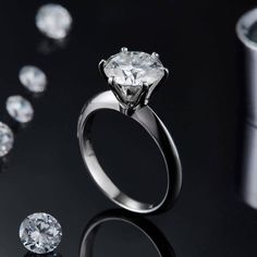 an engagement ring surrounded by diamonds on a black surface