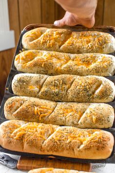 several hot dogs in buns on a baking sheet with cheese and herbs sprinkled on them