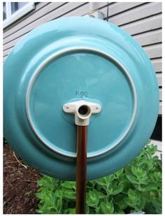 a blue frisbee is attached to a pole in front of a house with green plants