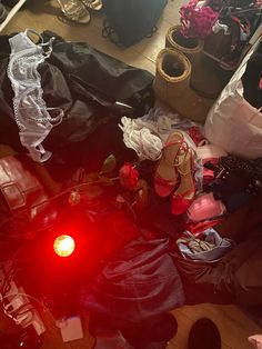 a pile of clothes and shoes sitting on the floor in front of a red light