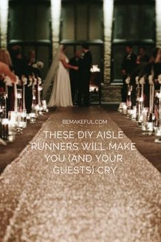 a bride and groom standing at the end of an aisle with candles in front of them