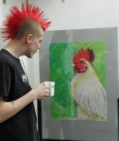 a man with red mohawks holding a coffee cup in front of a rooster painting