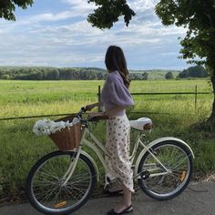 a woman standing next to a bike with flowers in the basket on the handlebars