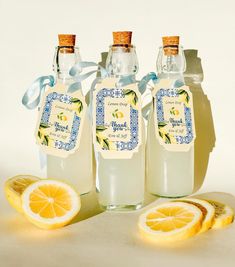 three bottles of lemonade sitting next to sliced lemons