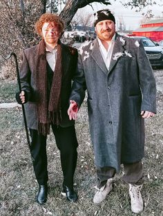 two people standing next to each other in the grass with one holding a walking stick