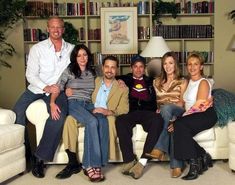 a group of people sitting on top of couches in a living room next to bookshelves