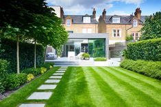 a large lawn with stepping stones in front of it and a house behind the grass