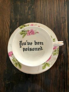 a teacup with the words you're been prisoned on it sitting on a wooden table