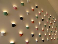 many cups are arranged on the wall with lights