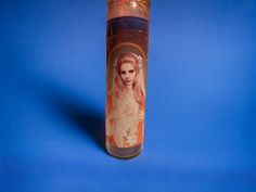 a candle with an image of the virgin mary on it is shown against a blue background