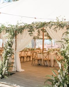 the inside of a tent decorated with white flowers and greenery