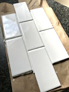 some white tiles laying on top of a brown paper bag next to a black counter