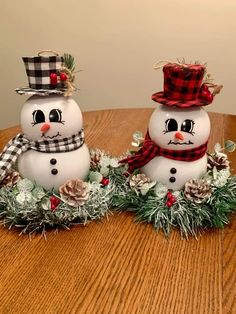 two snowmen sitting on top of a wooden table