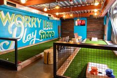 an indoor play area with green grass and blue walls that says worry land day more