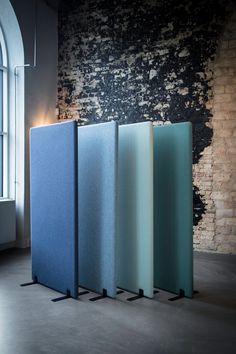 four different colored glass panels in front of a brick wall with an arched window behind them