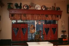 a kitchen with red cabinets and black counter tops in front of a window that has hearts on it