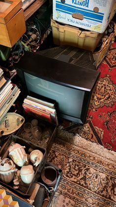 an old tv sitting on top of a table next to books and other items in a drawer